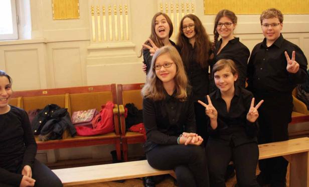 Eine Gruppe Jugendlicher posiert in schwarzen Hemden für ein Foto.