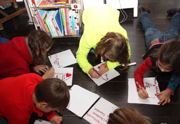 Kinder liegen auf dem Boden und schreiben Weihnachtskarten.