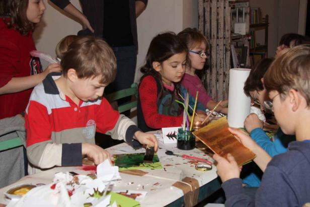 Eine Gruppe Kinder bastelt und malt an einem Tisch.