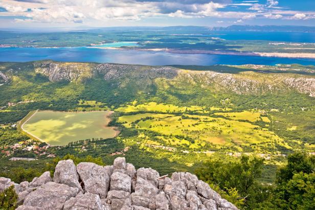Blick von einem Berg auf einen See und die Küstenlinie Kroatiens.