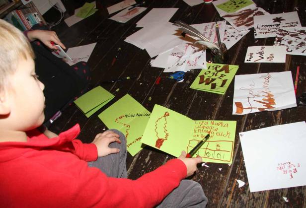 Ein Kind sitzt auf dem Boden und bastelt Weihnachtskarten.