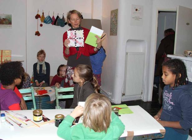 Eine Frau zeigt einer Gruppe von Kindern eine Papierdekoration.