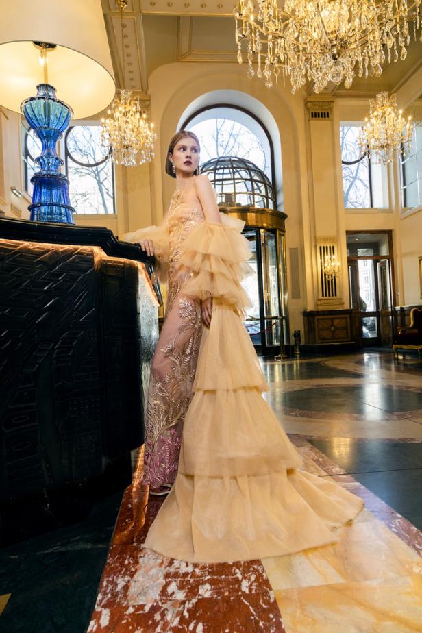 Eine Frau in einem eleganten, rüschenbesetzten Kleid in einer opulenten Hotellobby.