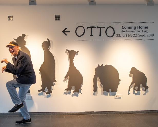 Otto Waalkes posiert vor einer Wand mit Silhouetten seiner Comicfiguren und dem Schriftzug „OTTO Coming Home“.