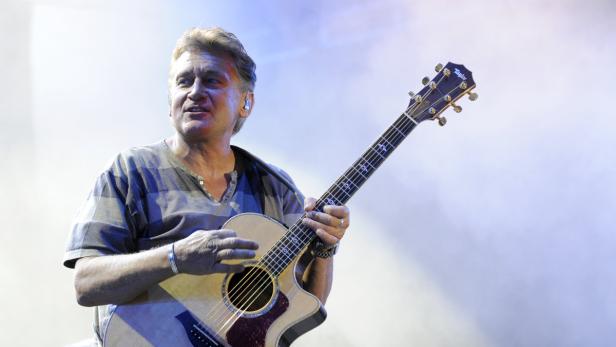 Ein Mann mittleren Alters spielt auf einer Akustikgitarre.