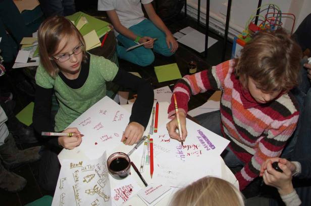 Kinder schreiben Weihnachtskarten mit Grüßen in verschiedenen Sprachen.