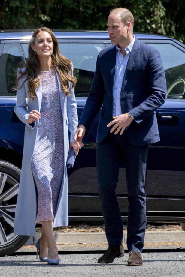 Prinz William und Prinzessin Kate halten Händchen vor einem dunklen Auto.