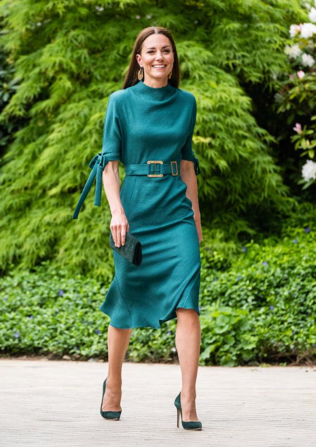 Kate Middleton in einem grünen Kleid mit passenden Schuhen und Clutch.
