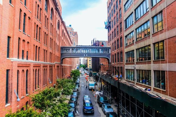 Blick auf eine Straße in New York mit einer Fußgängerbrücke zwischen zwei Backsteingebäuden.