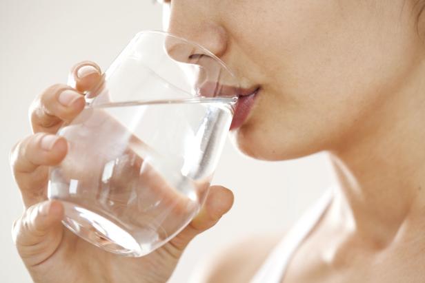 Eine Frau trinkt ein Glas Wasser.
