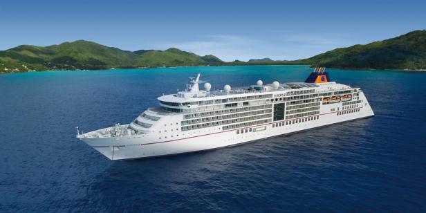 Das Kreuzfahrtschiff Europa 2 fährt auf dem Meer vor einer tropischen Insel.