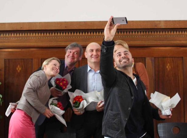 Eine Gruppe von Personen macht ein Selfie mit Blumensträußen in der Hand.