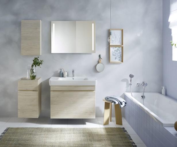 Ein helles Badezimmer mit Waschbecken, Spiegel, Badewanne und Holzdetails.