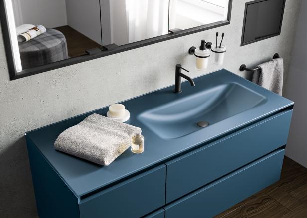 Ein blaues Waschbecken mit Armatur, Handtuch, Seife und einer kleinen Flasche im Badezimmer.