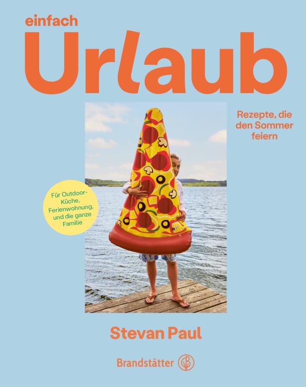 Ein Mann hält eine aufblasbare Pizza vor einem See.