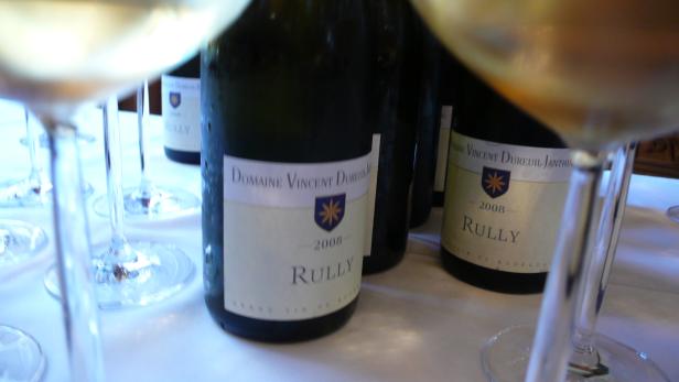 Mehrere Flaschen Rully 2008 von Domaine Vincent Dureuil stehen auf einem Tisch mit Weingläsern.