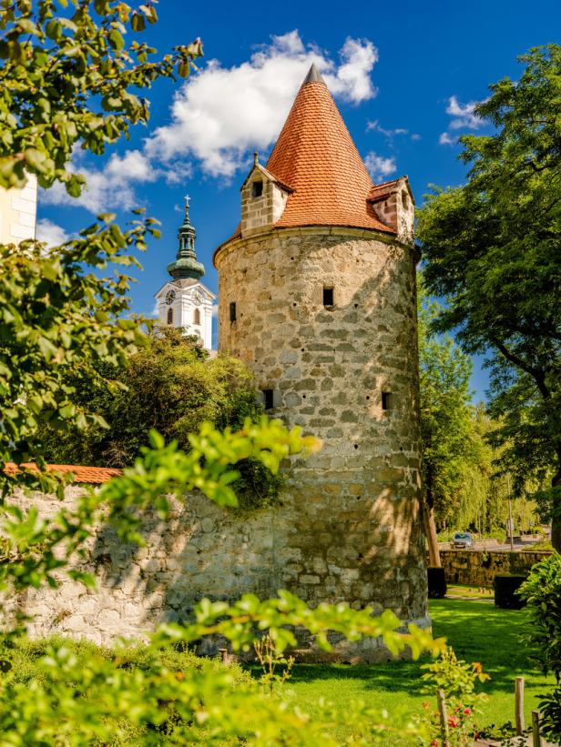 Ein mittelalterlicher Turm mit rotem Ziegeldach vor blauem Himmel.