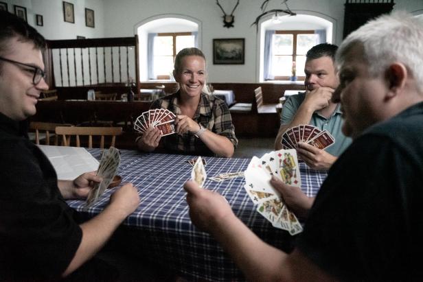 Eine Gruppe von Personen sitzt an einem Tisch und spielt Karten.