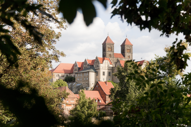 Die romanische Stiftskirche St. Cyriakus in Gernrode, umrahmt von Bäumen.
