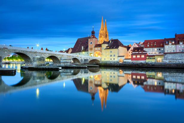Die Steinerne Brücke und der Regensburger Dom spiegeln sich im Wasser.