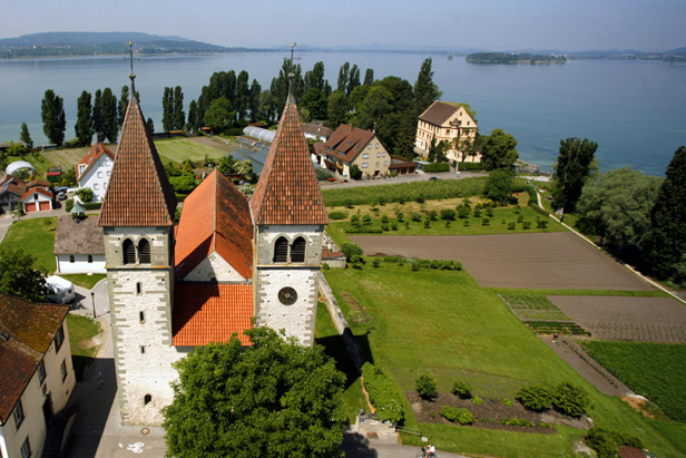 Luftaufnahme der Stiftskirche St. Peter und Paul in Reichenau mit Blick auf den Bodensee.
