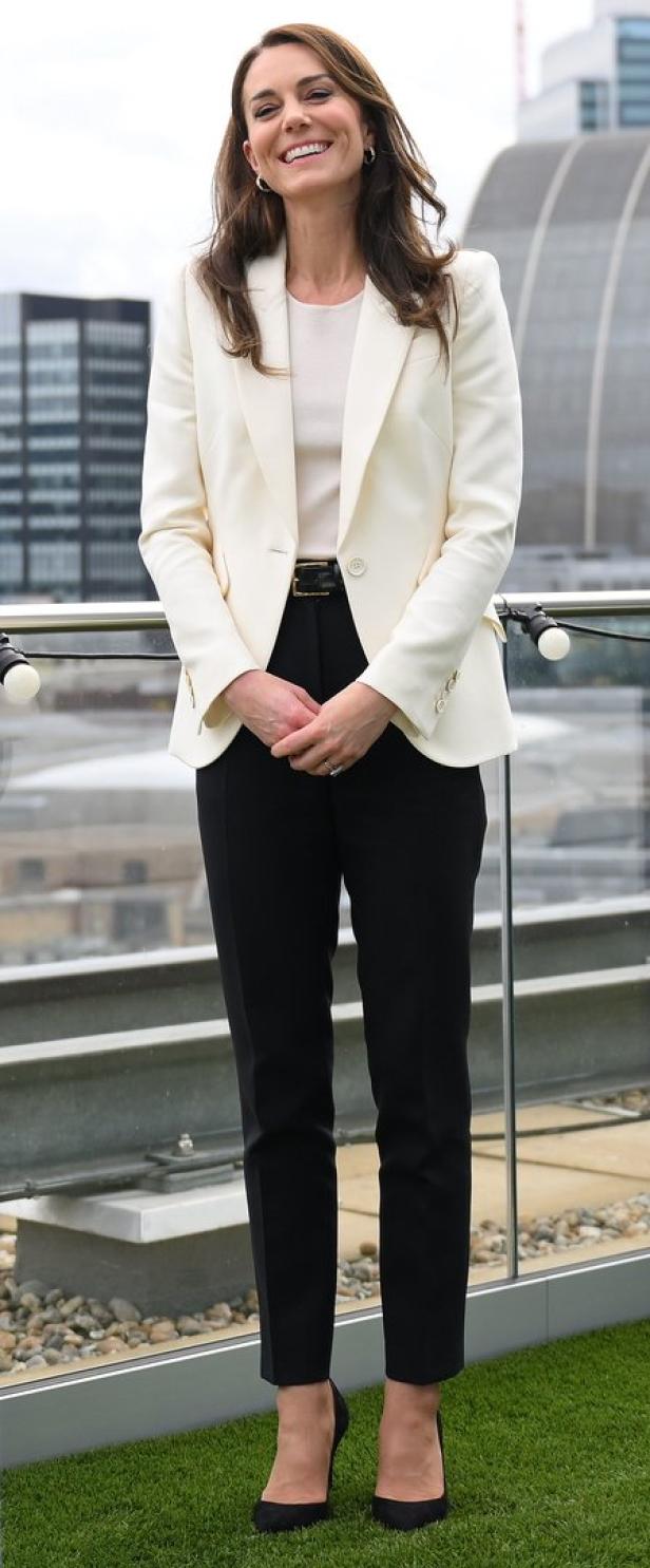 Kate Middleton trägt einen weißen Blazer und schwarze Hose auf einer Dachterrasse.