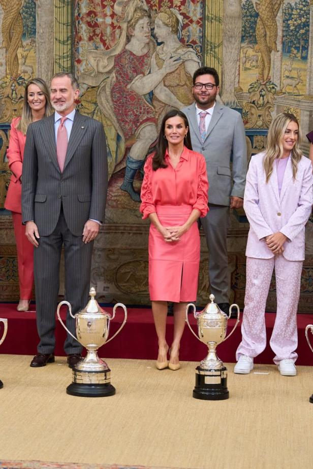 König Felipe und Königin Letizia von Spanien posieren mit anderen Personen und Trophäen vor einem Wandteppich.