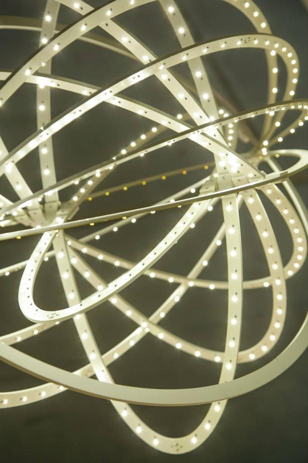 Eine sphärische Lampe mit mehreren LED-bestückten Ringen leuchtet.