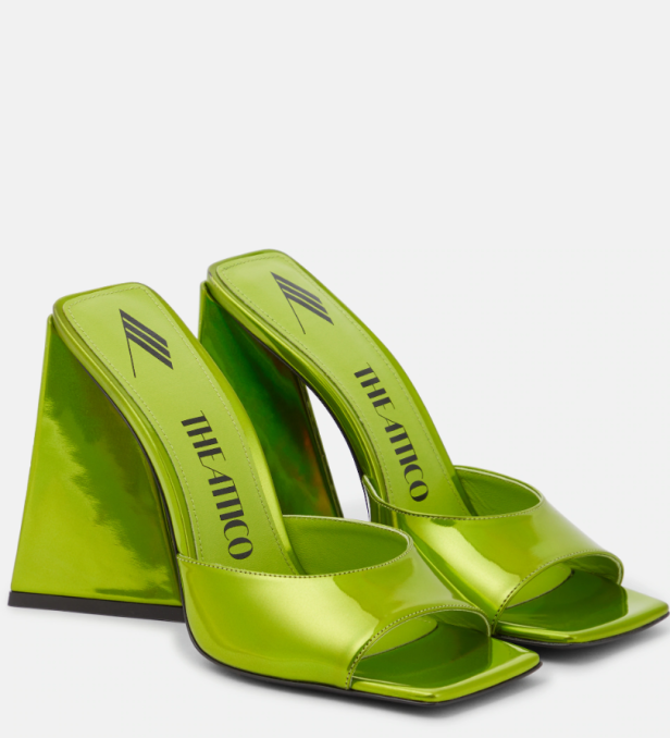 Ein Paar grüne „The Attico“ Mules mit ungewöhnlichen, dreieckigen Absätzen.