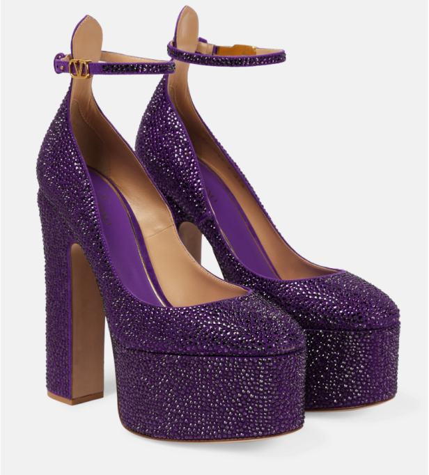 Ein Paar lilafarbene Plateau-Pumps mit Strass und Knöchelriemen stehen vor einem weißen Hintergrund.