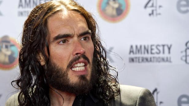 Porträt von Russell Brand vor einem Amnesty International Banner.