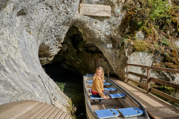 Eine Frau sitzt in einem Boot in der Nähe einer Grotte.