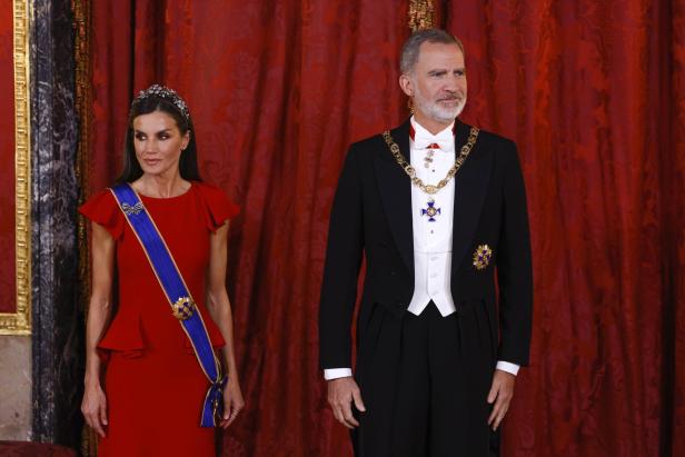 König Felipe VI. und Königin Letizia von Spanien posieren vor einem roten Vorhang.