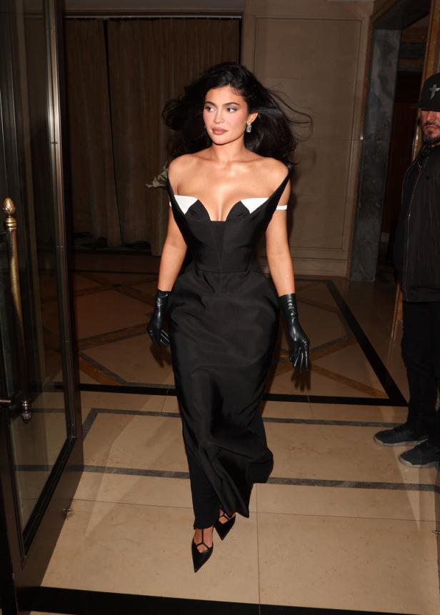 Kylie Jenner in einer eleganten schwarzen Robe und Handschuhen.