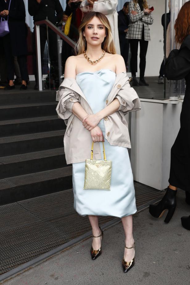 Emma Roberts trägt ein hellblaues Kleid und eine goldene Handtasche.