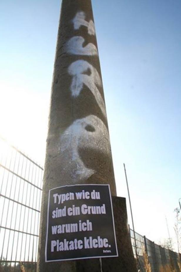 Ein Betonpfeiler mit Graffiti und einem Plakat mit der Aufschrift „Typen wie du sind ein Grund, warum ich Plakate klebe.“.