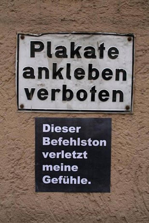 Ein Schild verbietet das Ankleben von Plakaten, darunter hängt ein Zettel mit der Aufschrift „Dieser Befehlston verletzt meine Gefühle.“.