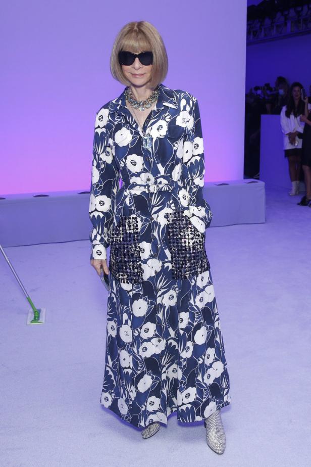 Anna Wintour trägt ein blau-weißes Blumenkleid und eine Sonnenbrille.