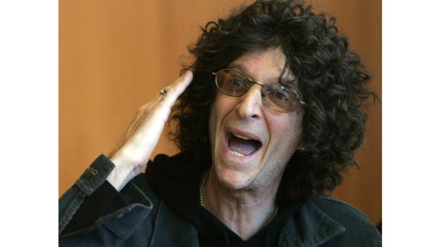 Howard Stern gestikuliert mit der Hand vor einem orangefarbenen Hintergrund.