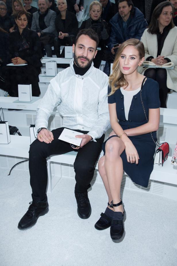 Ein Mann und eine Frau sitzen bei einer Chanel-Modenschau in der ersten Reihe.