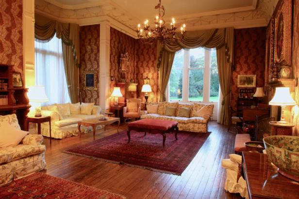 Ein elegantes Wohnzimmer mit antiken Möbeln und einem großen Fenster.