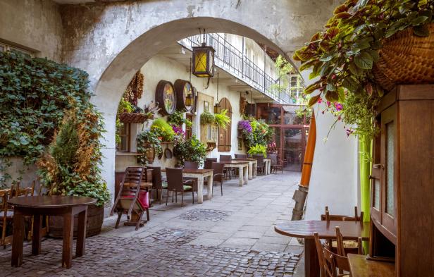 Ein Innenhof mit Tischen und Stühlen, dekoriert mit Pflanzen und rustikalen Elementen.