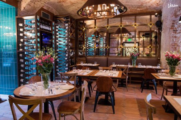Ein Innenraum eines Restaurants mit Tischen, Stühlen und Weinregalen.