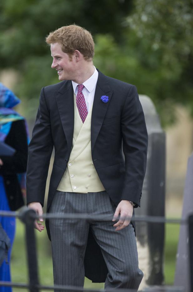 Prinz Harry in einem eleganten Anzug mit einer blauen Blume am Revers.