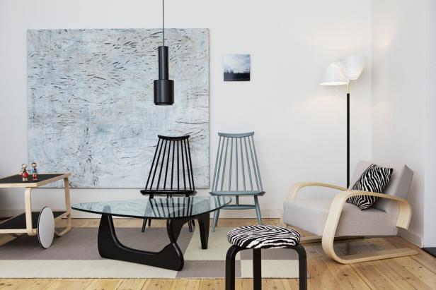 Ein Wohnzimmer mit modernen Möbeln, darunter Stühle, ein Tisch und ein Sessel.
