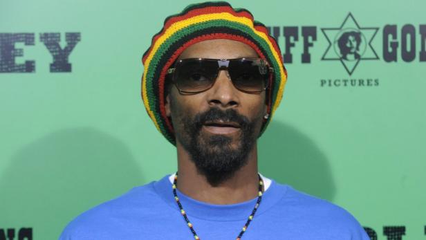 Snoop Dogg mit Sonnenbrille und Rastamütze vor einem grünen Hintergrund.