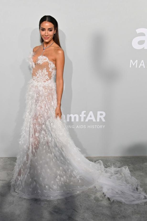 Eine Frau in einem weißen, federbesetzten Kleid auf dem roten Teppich.
