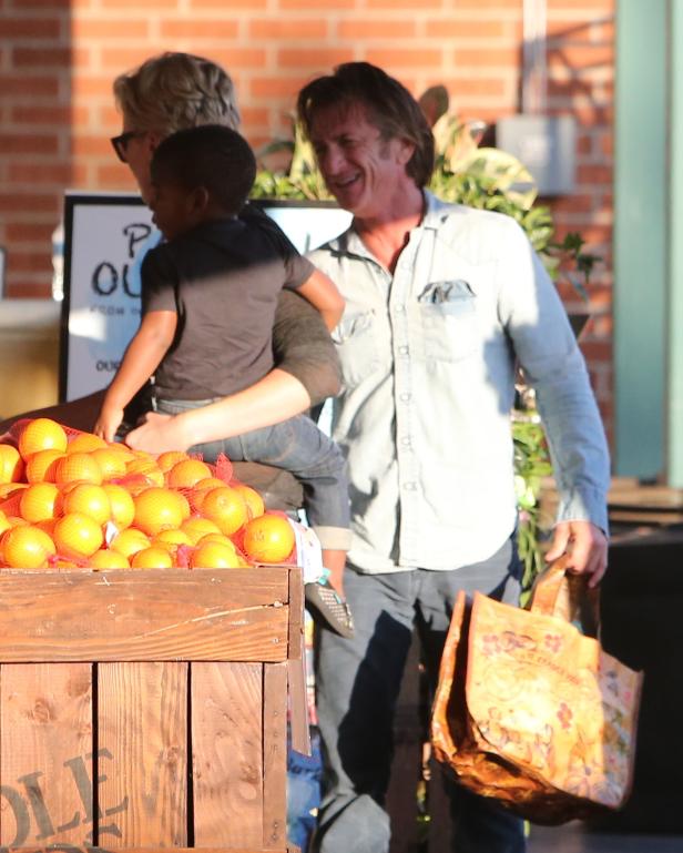 Sean Penn mit einem Kind an einem Orangenstand.