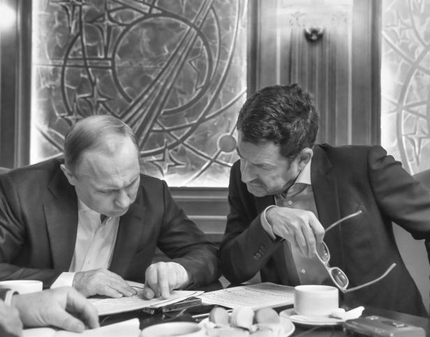 Wladimir Putin bei einem Treffen mit einem Mann am Tisch sitzend.