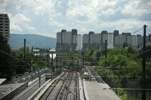 Blick auf eine Bahntrasse und Wohngebäude im Hintergrund.